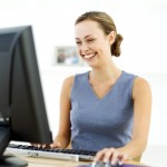 Young Woman Sitting in Front of a Computer and Laughing